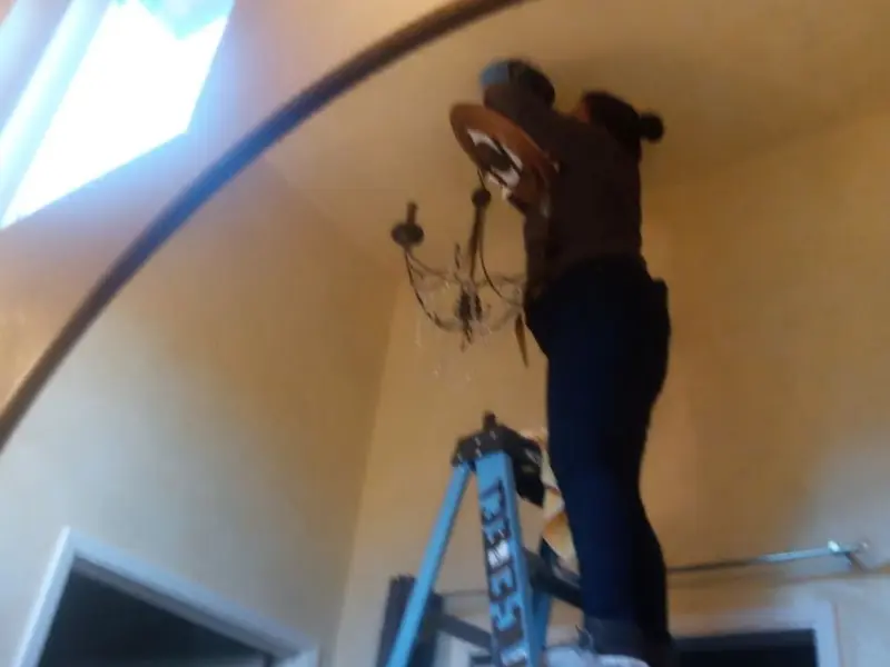Electrician installing a chandelier in a Pantops residence